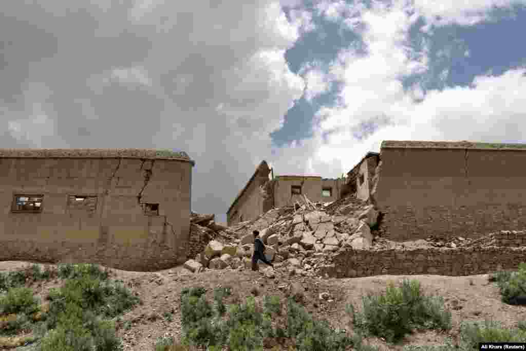 An Afghan man walks past a house in Gayan that was damaged in the earthquake.