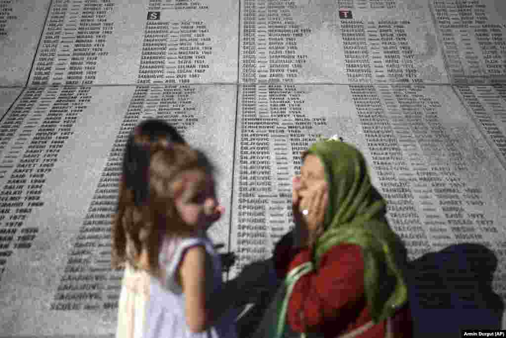 A woman prays next to a monument with the names of those killed in the Srebrenica genocide at the Memorial Center in Potocari. So far, 6,671 people have been identified and buried.