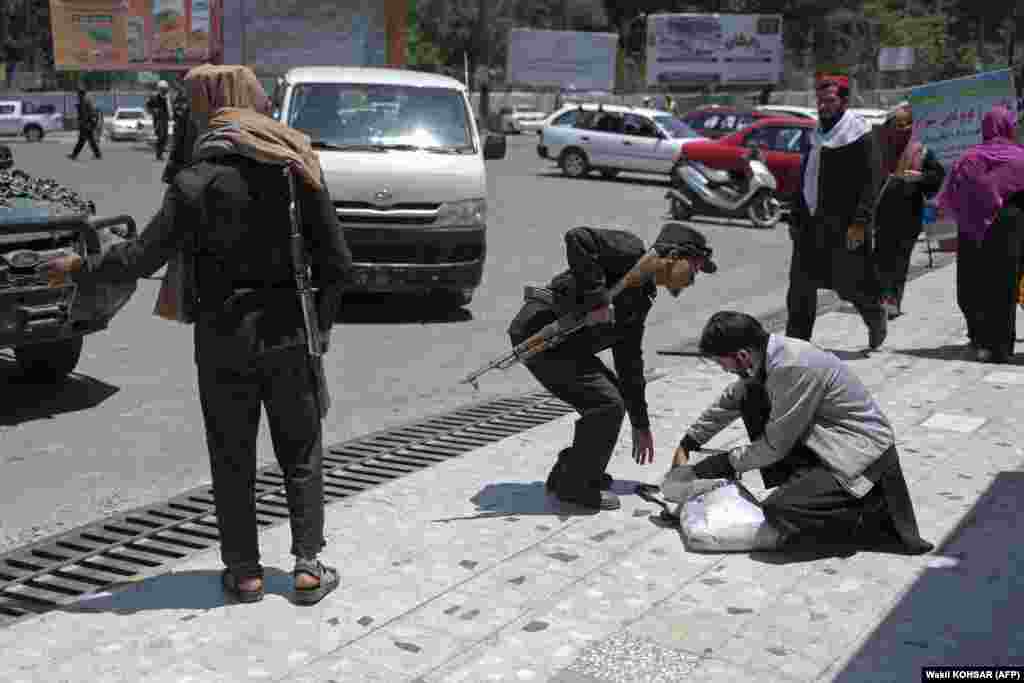 A Taliban fighter searches the belongings of a pedestrian along a blocked street ahead of a council meeting of tribal and religious leaders in Kabul on June 29.&nbsp;