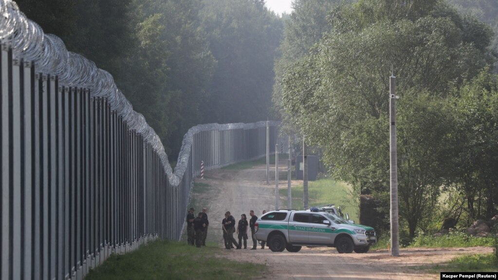Офицеры пограничной службы стоят у стены на польско-белорусской границе, 30 июня 2022 года