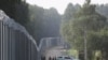 Lengyel határőrök állnak a határkerítés mellett belarusz határon a lengyelországi Kuznica közelében 2022. június 30-án