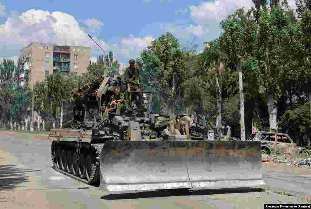 Separatist forces ride on top of a combat bulldozer in the city of Lysychansk.