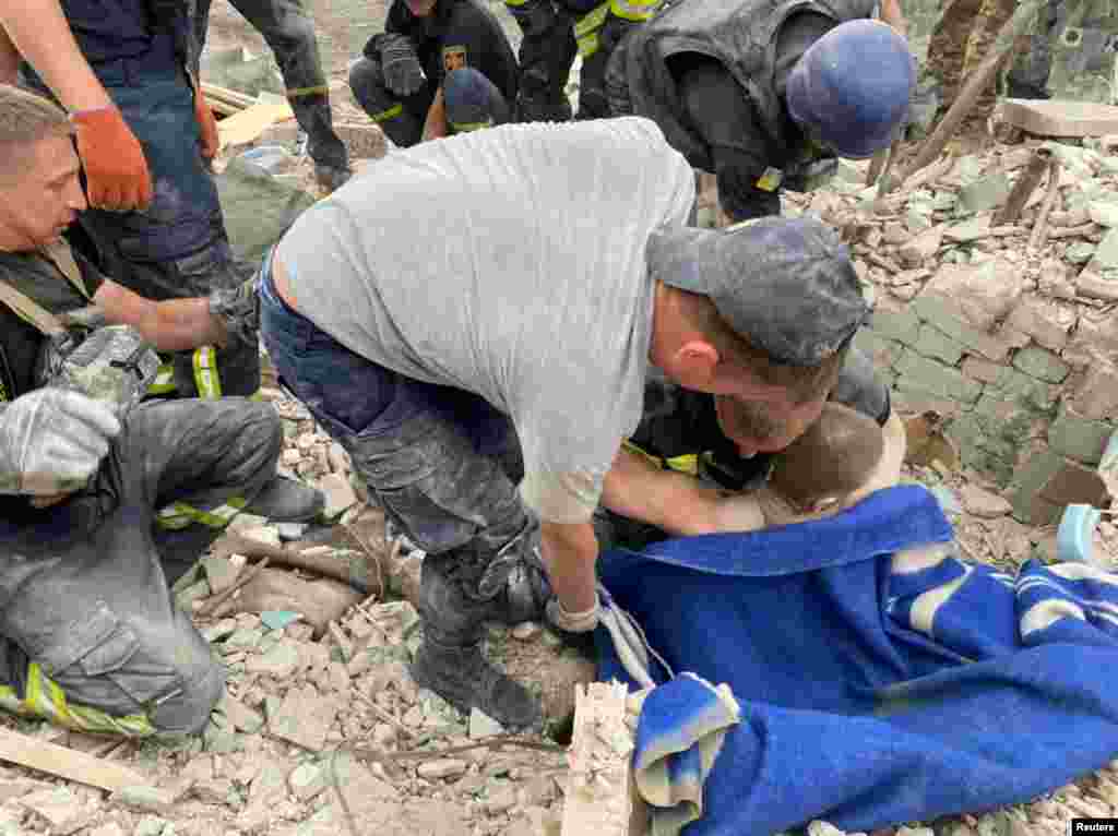 A mentőalakulatok egy sebesült férfit próbálnak kiemelni a romok alól Csasziv Jarban 2022. július 10-én
