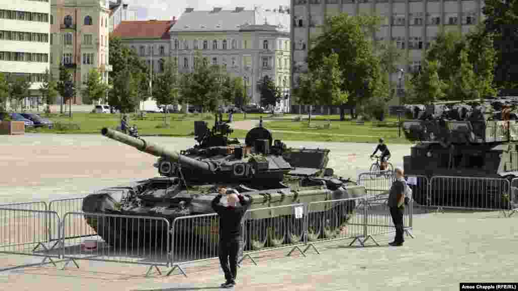 Câțiva oameni privesc un tanc rusesc T-90A avariat, expus într-un parc din centrul capitalei cehe, pe 11 iulie.&nbsp; O expoziție cu șase vehicule militare rusești avariate în timpul invaziei din Ucraina a fost deschisă oficial în cursul serii de Zdenek Hrib, primarul orașului Praga.