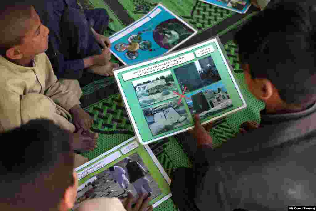 Children look at materials warning about the dangers of land mines in a&nbsp;EORE class outside of Kabul.