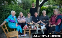 Lyudmyla Hevryasova (left) and her husband, Tolik Hevryasov (third right) join their neighbors for afternoon tea outside their damaged apartment block.