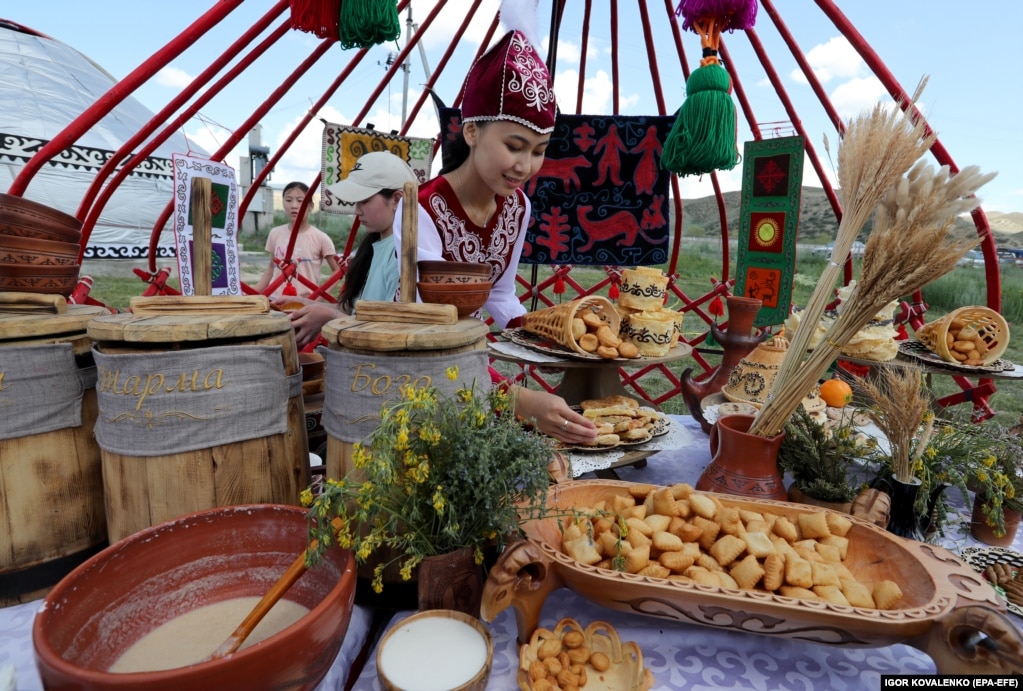 Девушка в национальной одежде продает посетителям традиционные блюда кыргызской кухни. Гобелены за ее спиной напоминают о богатстве кыргызской культуры