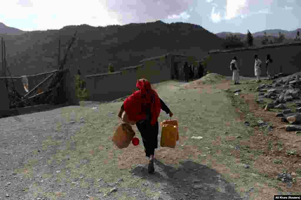 An Afghan girl carries empty water containers in the aftermath of the quake.