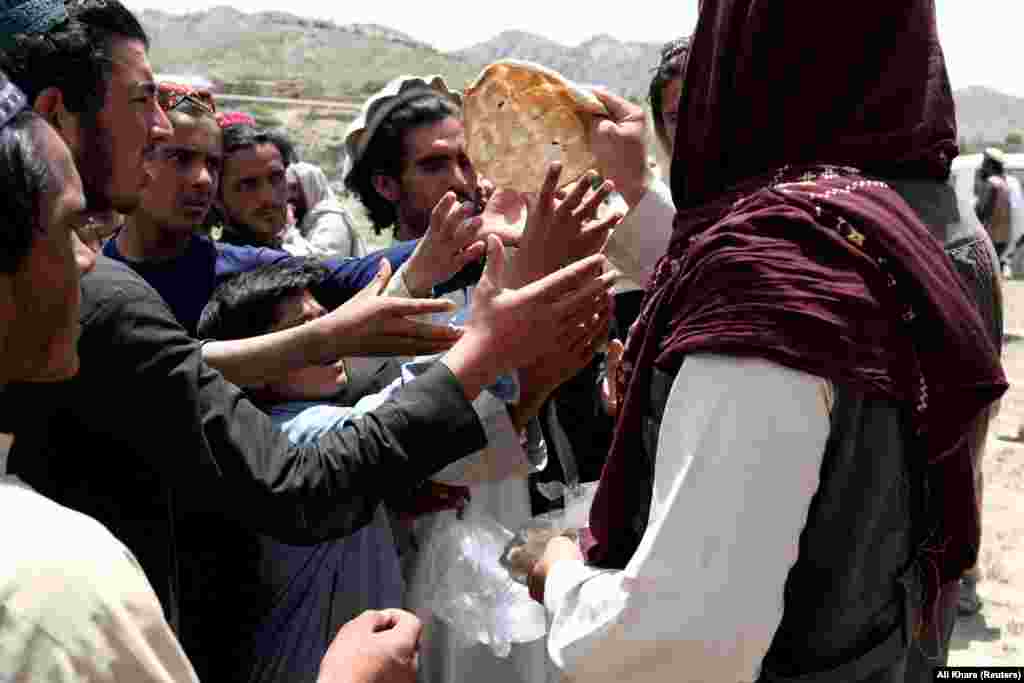 Afghan men receive bread from aid workers in an area affected by the earthquake.