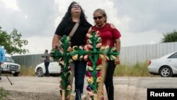 Članice lokalne zajednice Debra Ponce, lijevo, i Angelita Olvera žale nakon što su postavile krstove i sveće na mjesto gdje su desetine ljudi pronađeni mrtvi u kamionu s prikolicom u San Antoniju, Teksas, SAD. 28. juna