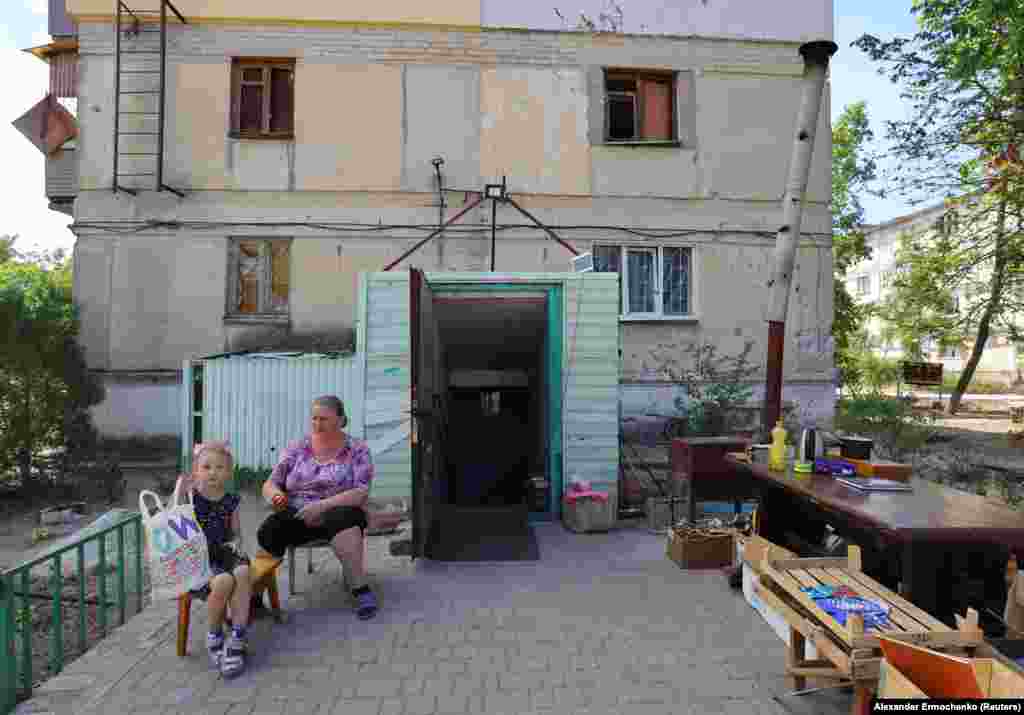 Locuitorii unui bloc stau afară, în fața clădirii avariate de bombardamentele rusești din Severodonețk, Ucraina, 30 iunie 2022.