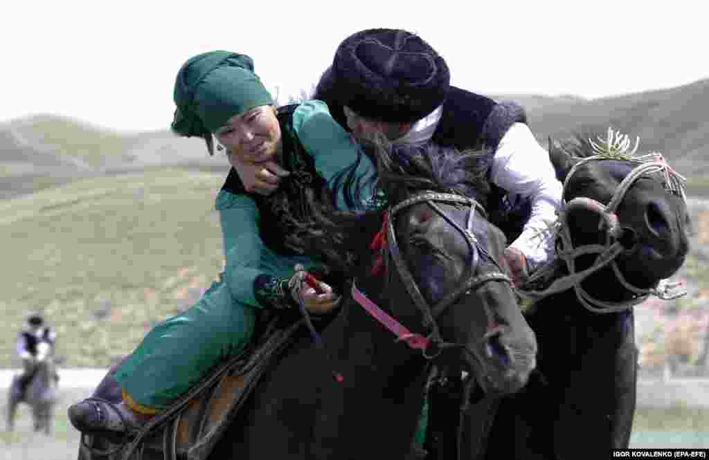 A Kyrgyz man latches onto a woman as they ride their horses in the national game of &quot;kyz kuumai&quot; (girl chasing).