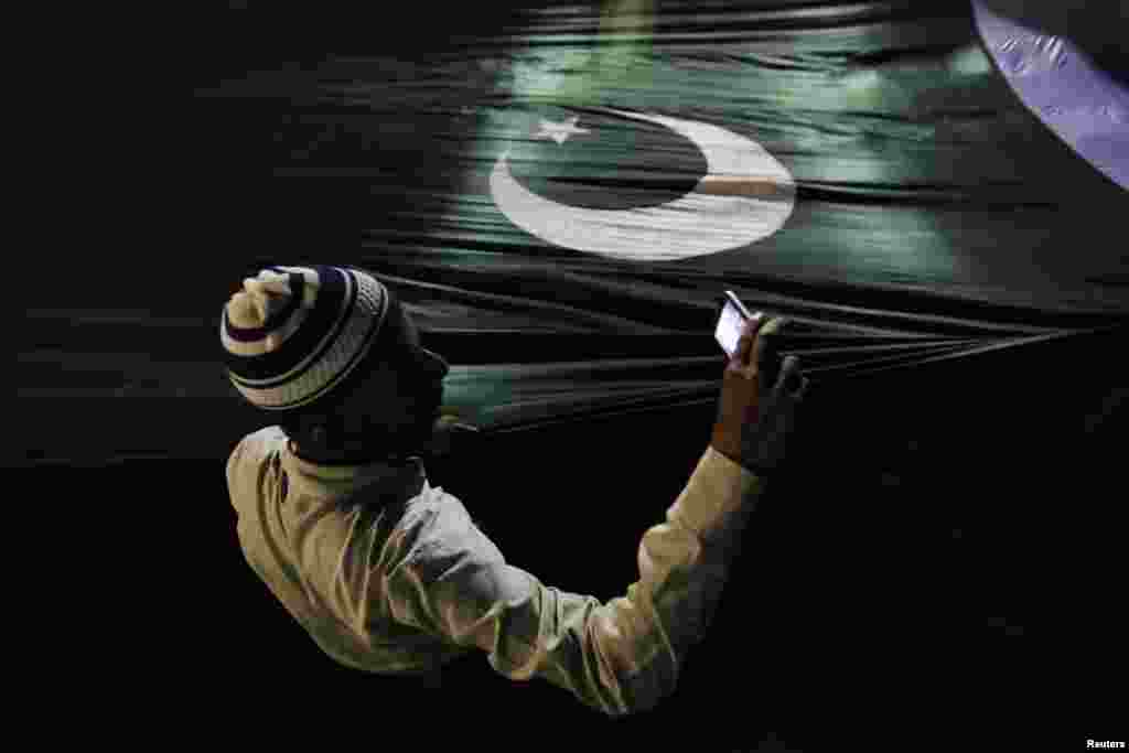 A supporter of the religious political party Jamaat-e Islami takes pictures with a mobile phone as he holds Pakistan's national flag during an election campaign rally in Karachi. Pakistan's general election will be held on May 11. (Reuters/Akhtar Soomro)
