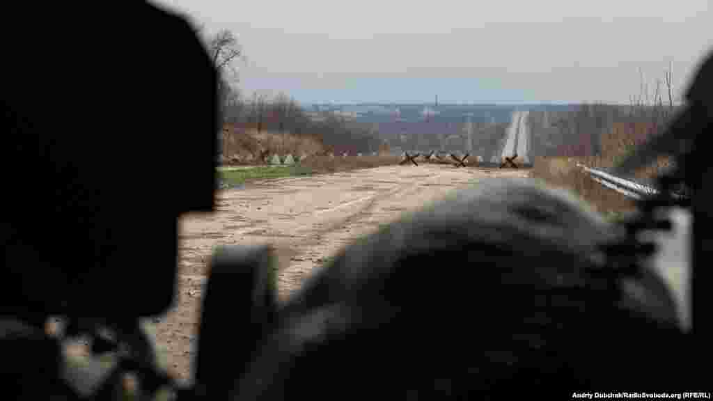 Погляд з блокпосту на дорогу, яка веде до розв&rsquo;язки на Ясинувату (контрольовану проросійськими бойовиками). Будівлі і труба ліворуч &ndash; це Донецька фільтраційна станція