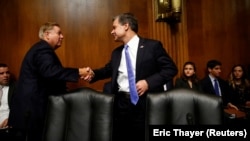 Директор ФБР Кристофер Рэй (справа) обменивается рукопожатием с сенатором Линдси Грэмом перед началом слушаний в Сенате.