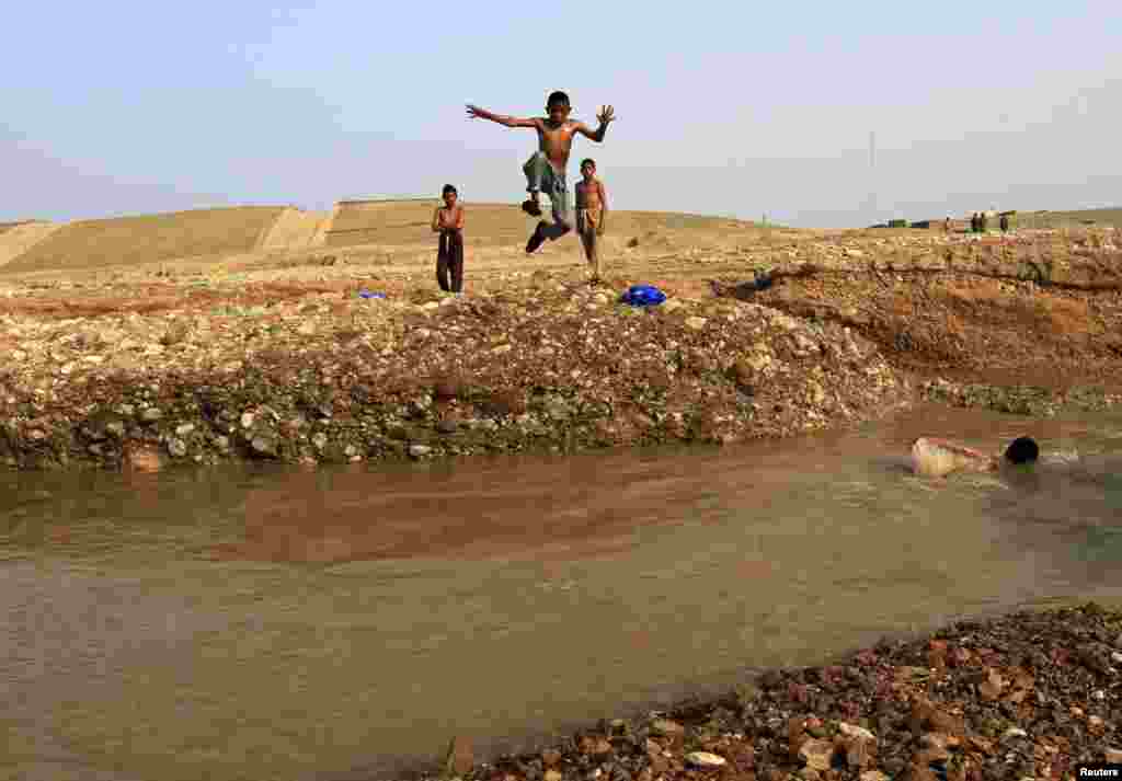 An Afghan boy jumps into muddy water as he goes for a swim with friends on the outskirts of Jalalabad. (Reuters/Parwiz)