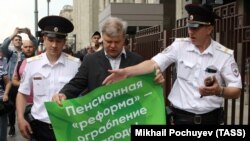 Sergei Mitrokhin (center), head of the Moscow branch of the Yabloko Party, is detained by police outside the State Duma in Moscow on June 19 after a one-person protest against pension reform.