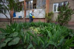 79-річна Марія Іванівна поливає квіти під своїм балконом