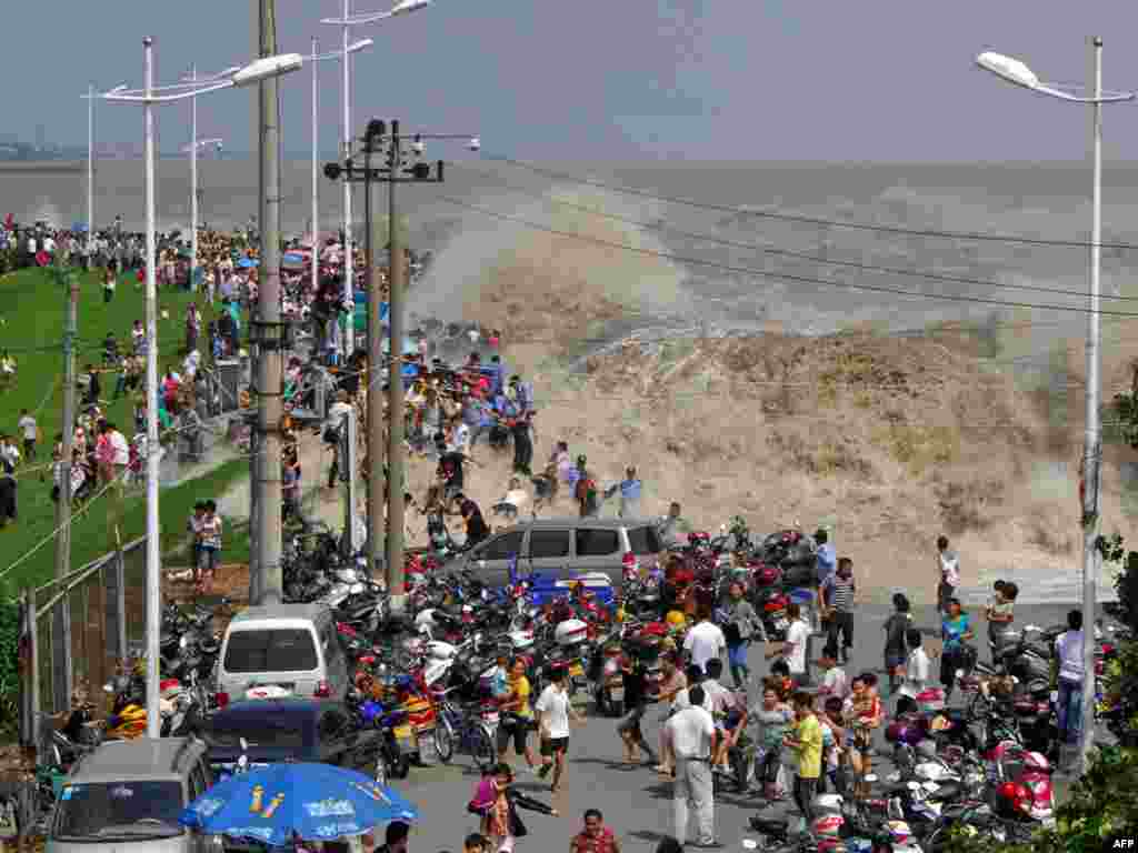 Tourists run away as a surging tide breaks through a dam on the Qiangtang River in China's Zhejiang Province. Experiencing the tidal bore is an annual tradition for residents living nearby. (Photo by AFP)