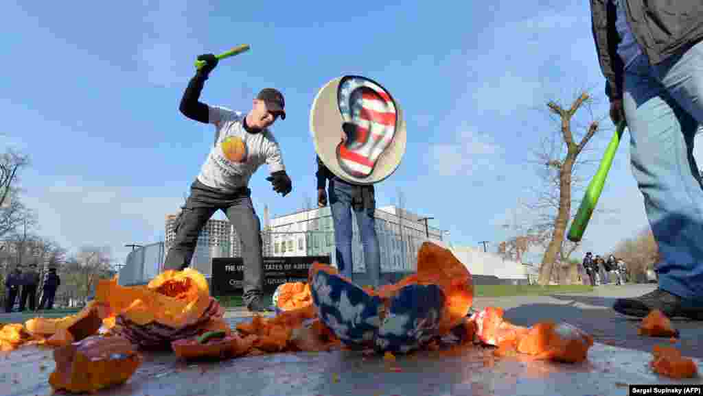 Ukrainian activists from the Internet Party of Ukraine smash a pumpkin with headphones as they stage a demonstration in front of the U.S. Embassy in Kyiv on November 1. (AFP/Sergei Supinsky)