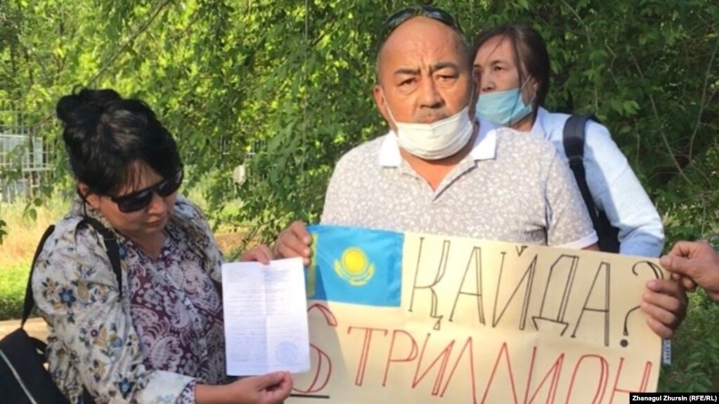 Активист Аскар Каласов держит плакат перед зданием департамента полиции в Актобе. 6 июня 2020 года