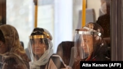 Passengers wearing face shields due to the COVID-19 coronavirus, sit inside a bus in the Iranian capital Tehran, June 22, 2020