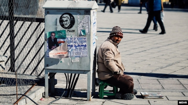 چسباندن پوستر در معابر عمومی شیوه‌ای رایج در تبلیغات انتخاباتی است، همدان، ۲۵ بهمن ۹۸