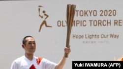 Јапонскиот кабуки актер Накамура Канкуро го пренесува олимпискиот пламен за време на церемонијата на пристигнување на штафетата во Токио, 23 јули 2021 година