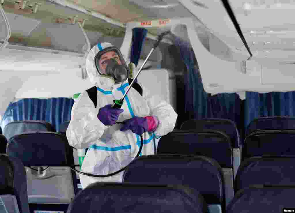 Працівниця в захисному костюмі розпорошує дезинфікуючий засіб всередині літака в міжнародному аеропорту &laquo;Бориспіль&raquo;