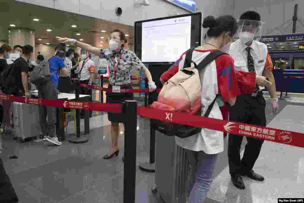 Сотрудники авиакомпаний направляют путешественников к пункту пропуска для пассажиров из районов повышенного риска, чтобы они предоставили свои результаты теста на COVID-19 перед тем, как зарегистрироваться на свой рейс в терминале №2 столичного аэропорта Пекина. В китайской столице в среду отменили более 60% коммерческих рейсов и повысили уровень оповещения на фоне новой вспышки коронавируса, сообщают государственные СМИ