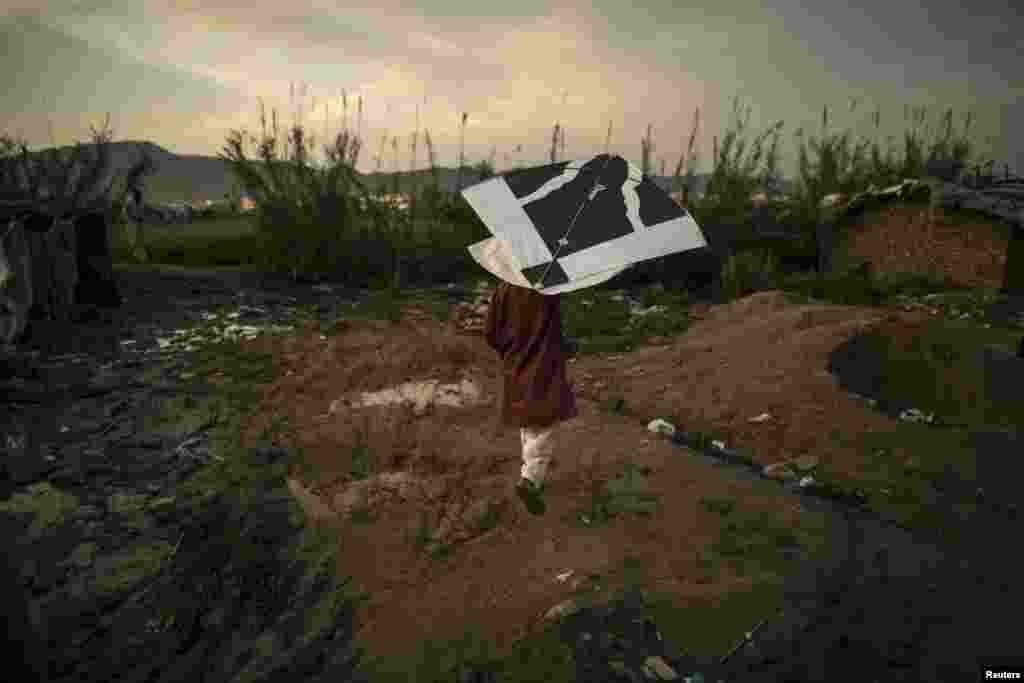 A Pakistani boy plays with his kite in a slum on the outskirts of Islamabad on March 30. (Reuters/​Zohra Bensemra)