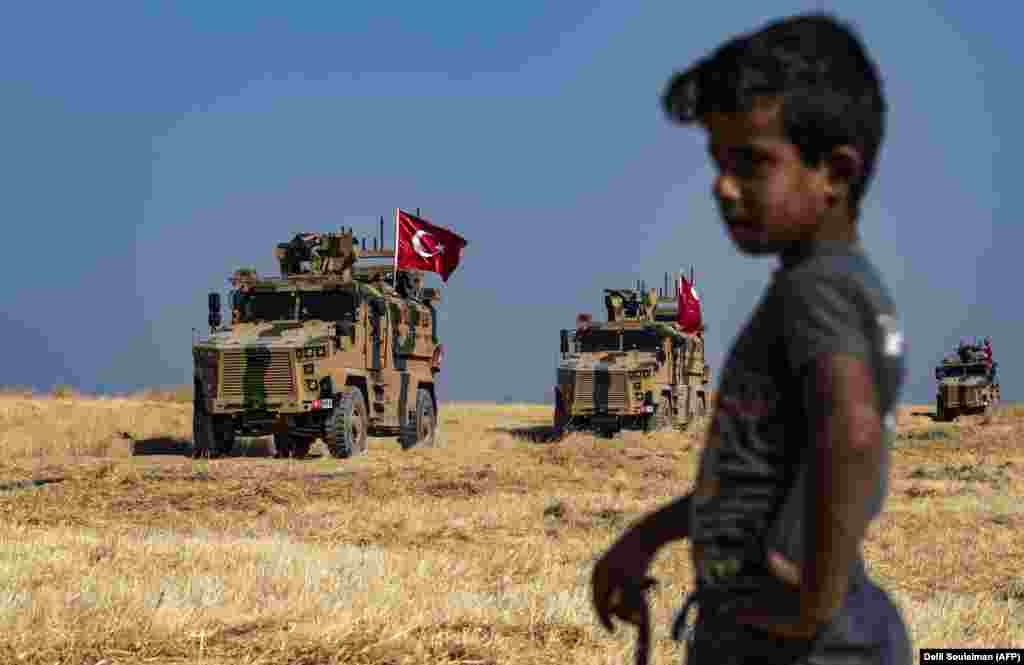 A Syrian boy watches as Turkish military vehicles, part of a U.S. military convoy, take part in a joint patrol in the Syrian village of Al-Hashisha on the outskirts of Tal Abyad, along the border with Turkey, on October 4. (AFP/Delil Souleiman)