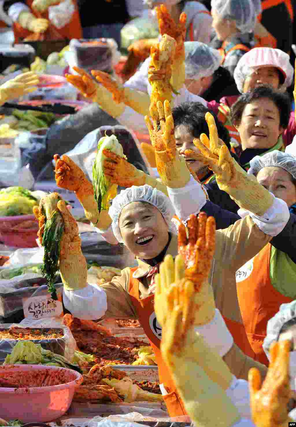 Volunteers pose as they make 140 tons of kimchi, a traditional dish of spicy fermented cabbage and radishes, in a park in Seoul, South Korea. City officials will hand out kimchi to about 14,000 poor households in an event marking the start of the winter season. (AFP/Jung Yeon-Je)