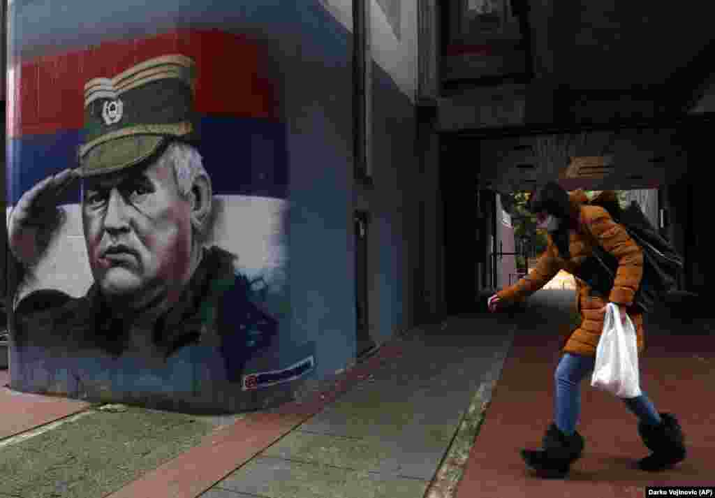 A woman walks past graffiti depicting former Bosnian Serb wartime General Ratko Mladic in Belgrade. Mladic was convicted by a UN war crimes tribunal in 2017 and sentenced to life in prison for masterminding crimes by Bosnian Serb forces throughout the war that left 100,000 dead. (AP/Darko Vojinovic)