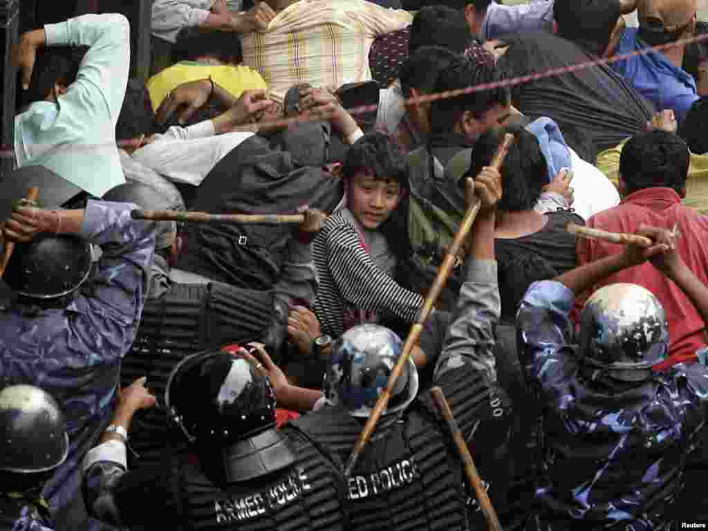 Nepali riot policemen beat pro-democracy activists after they were fired upon with tear gas for defying a curfew in Nepal's capital Kathmandu, April 22, 2006. Riot police clubbed and threw tear gas at tens of thousands of protesters as they shouted anti-monarch slogans while attempting to march towards the royal palace in protest of King Gyanendra. REUTERS/Adrees Latif