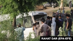 People gather at the scene after a bus carrying pilgrims of the Sikh minority, which was hit by a train, in the district of Sheikhupura in the eastern Punjab Province.