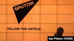 Человек на фоне логотипа российского новостного агентства Sputnik.