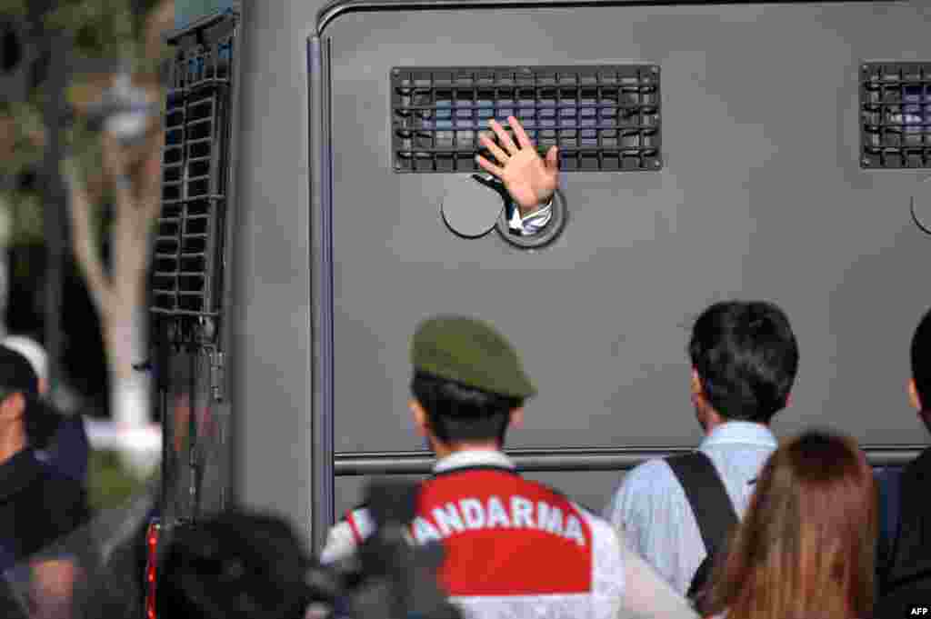 An Ergenekon prisoner being driven in a police armored vehicle waves at protesters as police and gendarmerie block access to the courthouse in Silivri, near Istanbul, where prosecutors delivered final arguments in the case against 275 people accused of plotting to overturn Turkey&#39;s Islamic-leaning government. (AFP/Ozan Kose)