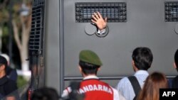 An Ergenekon prisoner being driven in a police armoured vehicle waves at protesters in August 2013 as police and gendarmerie block access to a courthouse in Silivri, near Istanbul.