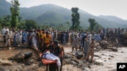 Salvatorii transportă trupul neînsuflețit al unei victime a viiturii de vineri, după ce l-au recuperat din dărâmăturile unei case avariate din satul Qadir Nagar, lângă Pir Baba, districtul Buner, în nord-vestul Pakistanului, sâmbătă, 16 august 2025.