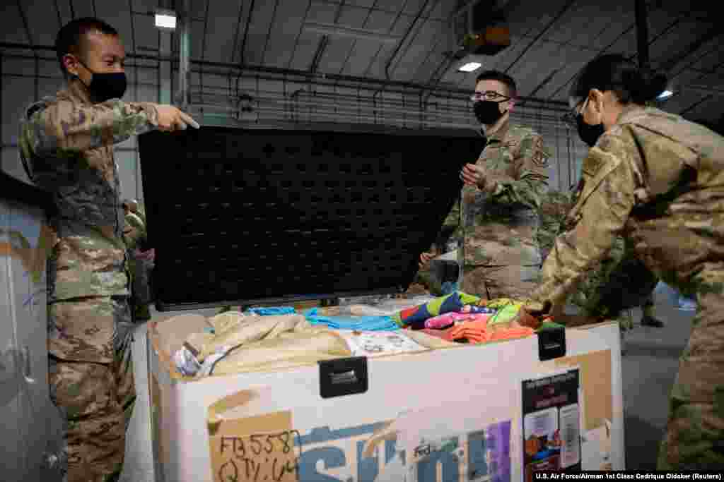 Militari ai Forțelor Aeriene din SUA ambalează o cutie plină cu îmbrăcăminte, donată pentru evacuații afgani, în baza Royal Air Force din Lakenheath, Anglia. &nbsp;