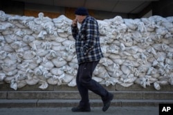 A local resident of Kherson passes by sandbags protecting a post office one year after Ukrainian troops liberated the city.