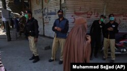 FILE: Police officers stand guard to try to enforce a nation-wide lockdown, at a market in Peshawar in April.