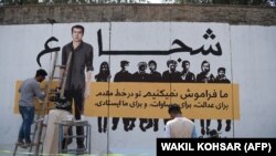 FILE: An Afghan artist paints on a barrier wall a mural with the image of slain Agence France-Presse (AFP) Afghanistan's chief photographer Shah Marai, who was killed along with other Afghan journalists in a targeted suicide bombing in Kabul.
