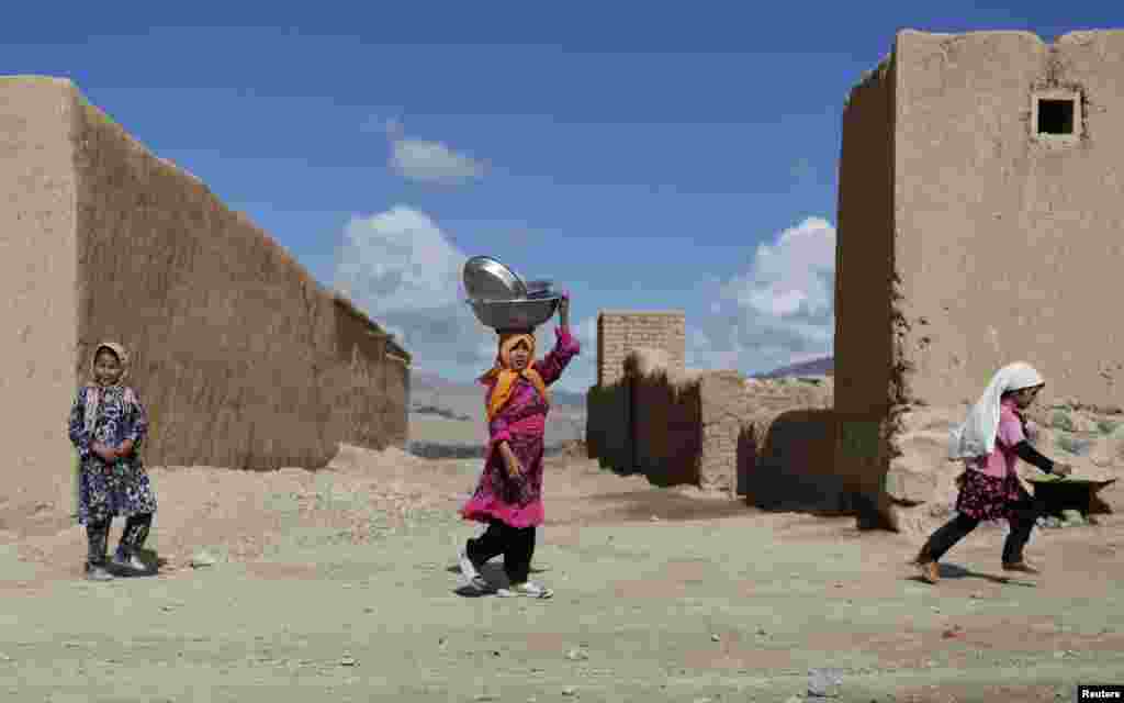 A girl carries kitchen equipment on her head in Bamiyan Province, Afghanistan. (Reuters/Mohammad Ismail)