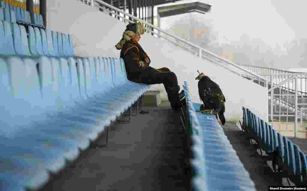 A hunter and his tamed golden eagle rest during an annual hunters' competition in Almaty, Kazakhstan. (Reuters/Shamil Zhumatov)