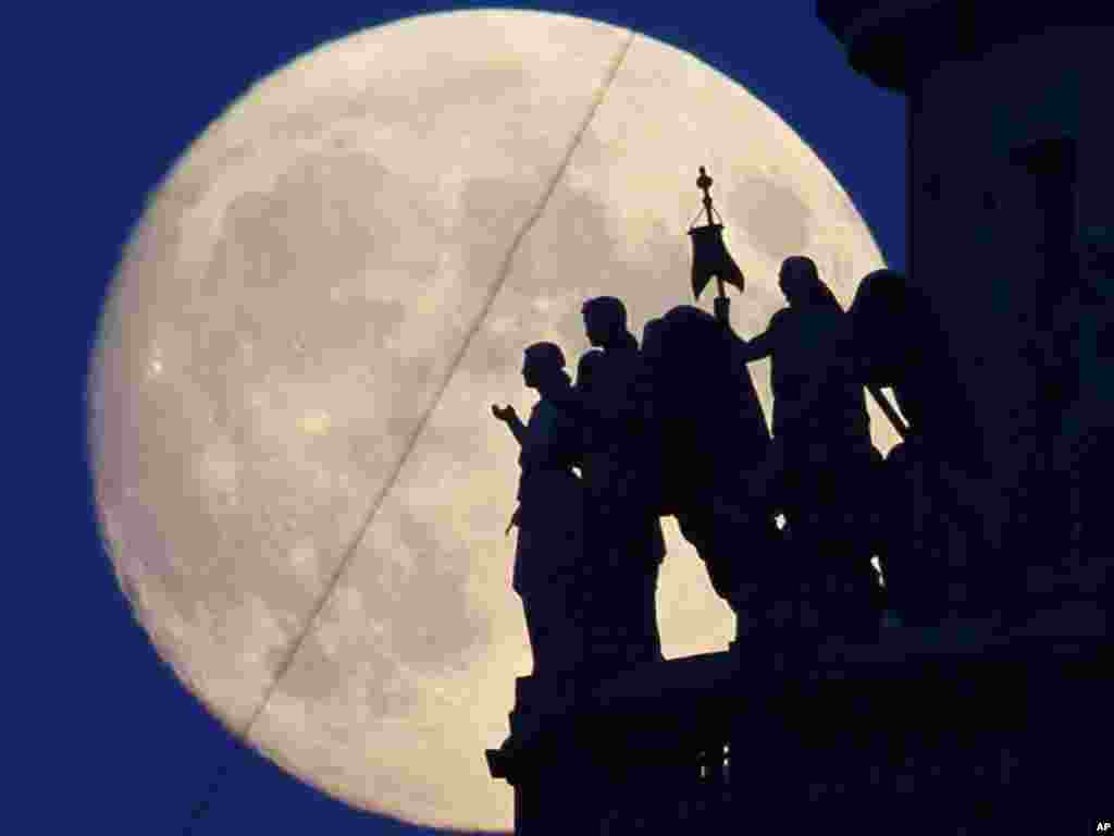 Statues of angels atop St. Isaak's Cathedral are silhouetted against the full moon in St. Petersburg, Russia, on June 15.Photo by Dmitry Lovetsky for AP