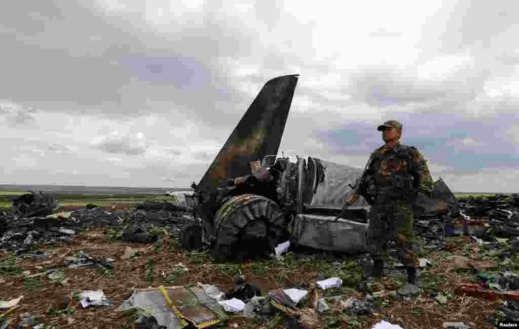An armed pro-Russian separatist guards the crash site one day after an IL-76 Ukrainian army transport plane was shot down by anti-Kyiv militants in Luhansk, killing all 49 troops aboard. (Reuters/Shamil Zhumatov)