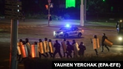 Riot police advance along a street in Minsk in the early hours of August 12.
