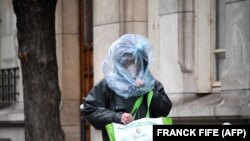 Un bărbat care se protejează cu o pungă de plastic merge pe o stradă din Paris, 21 martie